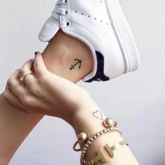 anchor tattoo on the ankle, heart tattoo on the wrist, small tattoo ideas for women, golden jewellery on the hand