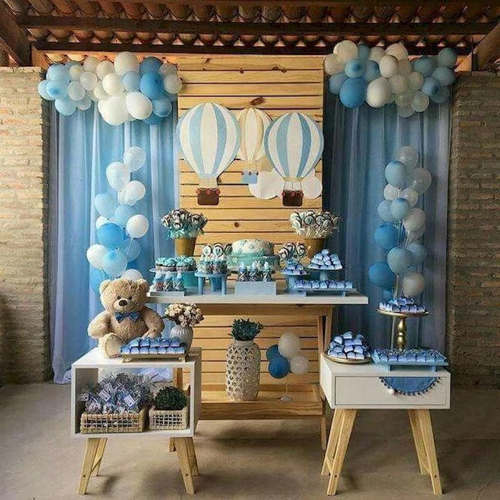 baby shower centerpieces boy, white and blue balloons, cake and sweets on the table, plush teddy bear