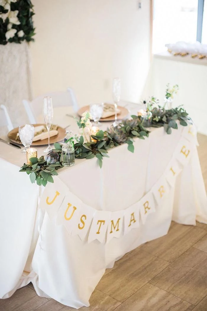 just married garland, green flower arrangement on the table with candles, wedding table settings