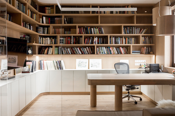 large wooden bookcase with many shelves and cupboards, wooden desk with mesh black chair, home office decor