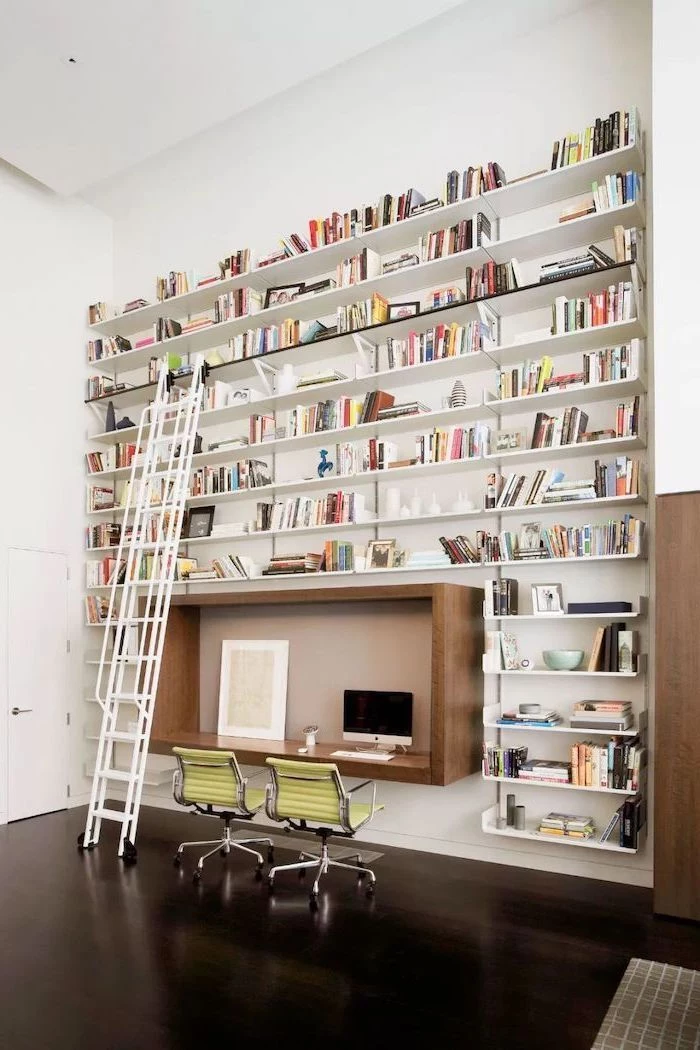 multiple bookshelves with books, sliding ladder, wooden desk, green chairs, home office decor