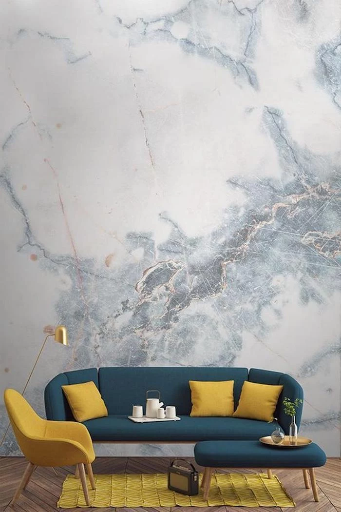 blue marble wallpaper, wall painting ideas, blue sofa with yellow throw pillows, yellow armchair and rug
