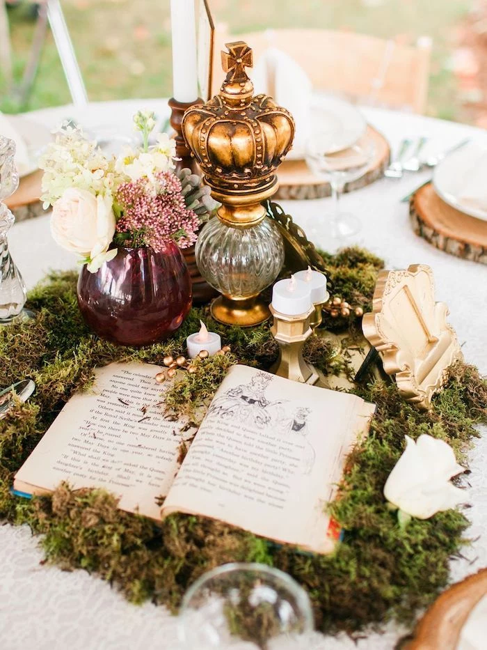centrepiece with moss and book, white and pink flower bouquet, glass goblet with a crown, outdoor wedding ideas