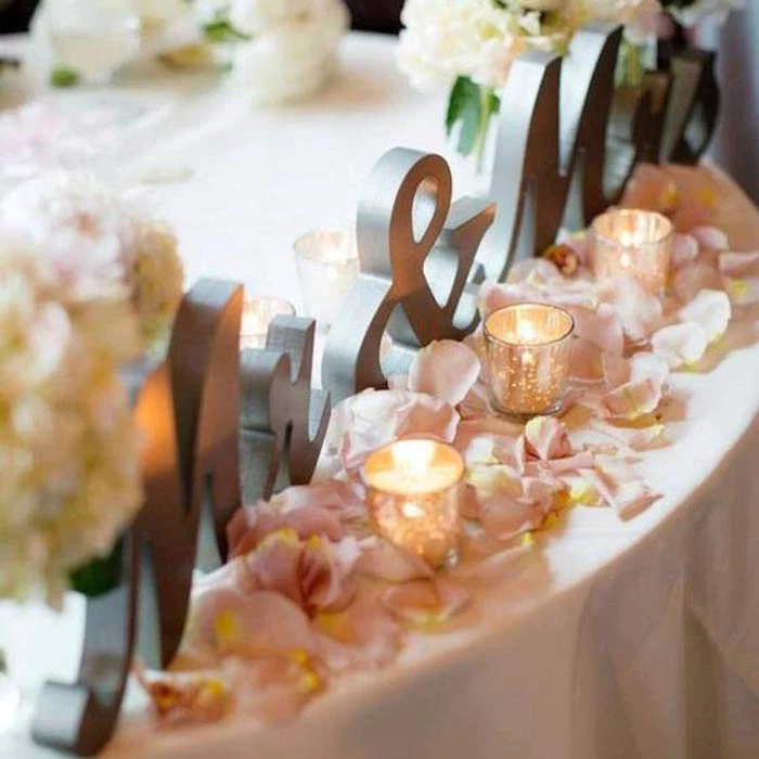 mr and mrs metal sign, rose petals on the table with candles, flower bouquets, wedding table settings