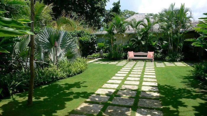 geometrical stone tiles in the grass, tall palm trees, landscape lighting ideas, patches of bushes