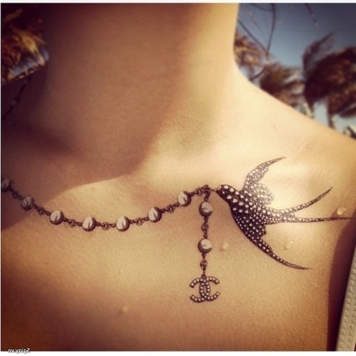pearl channel necklace, carried by a bird, chest tattoos for women, black and white dotted bird