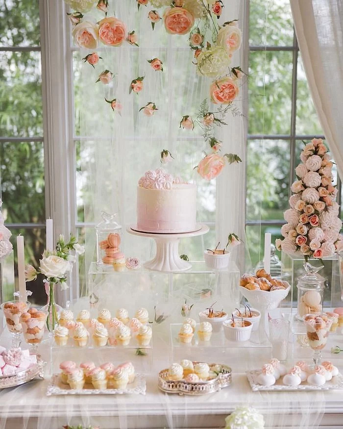cake on a cake stand, cupcakes on trays, hanging roses from the ceiling, wedding table decorations