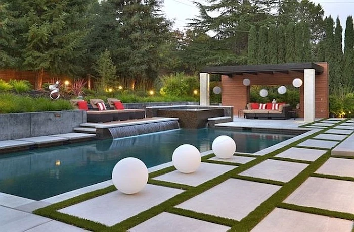 small patches of grass between the tiles, large pool, grass patch with bushes, pool landscaping ideas, tall trees