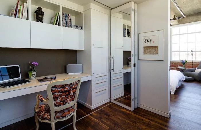 white cabinets and bookshelves, printed vintage chair, small home office desk, dark wooden floors