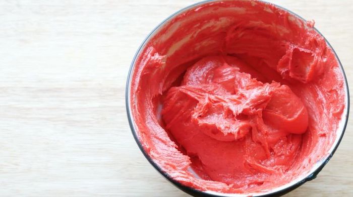 red cake batter in a bowl, wooden countertop, unicorn cake