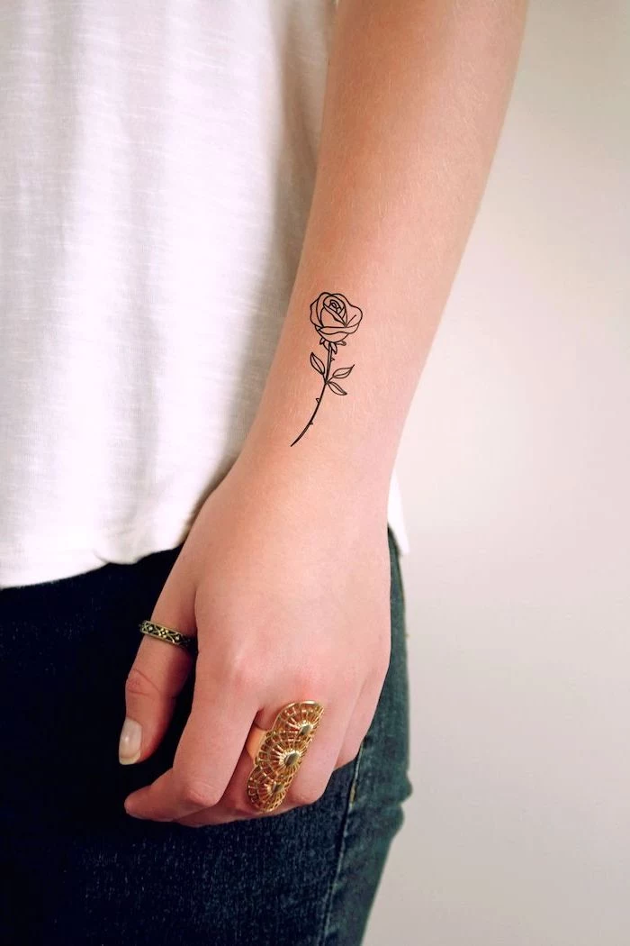 rose tattoo on the wrist, unique tattoos, white background and top, rings on the fingers