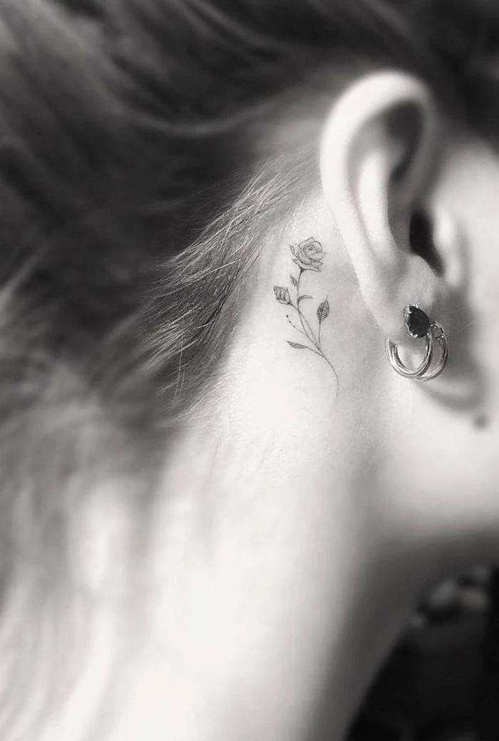 rose tattoo behind the ear, brown hair in a bun, arm tattoos for girls
