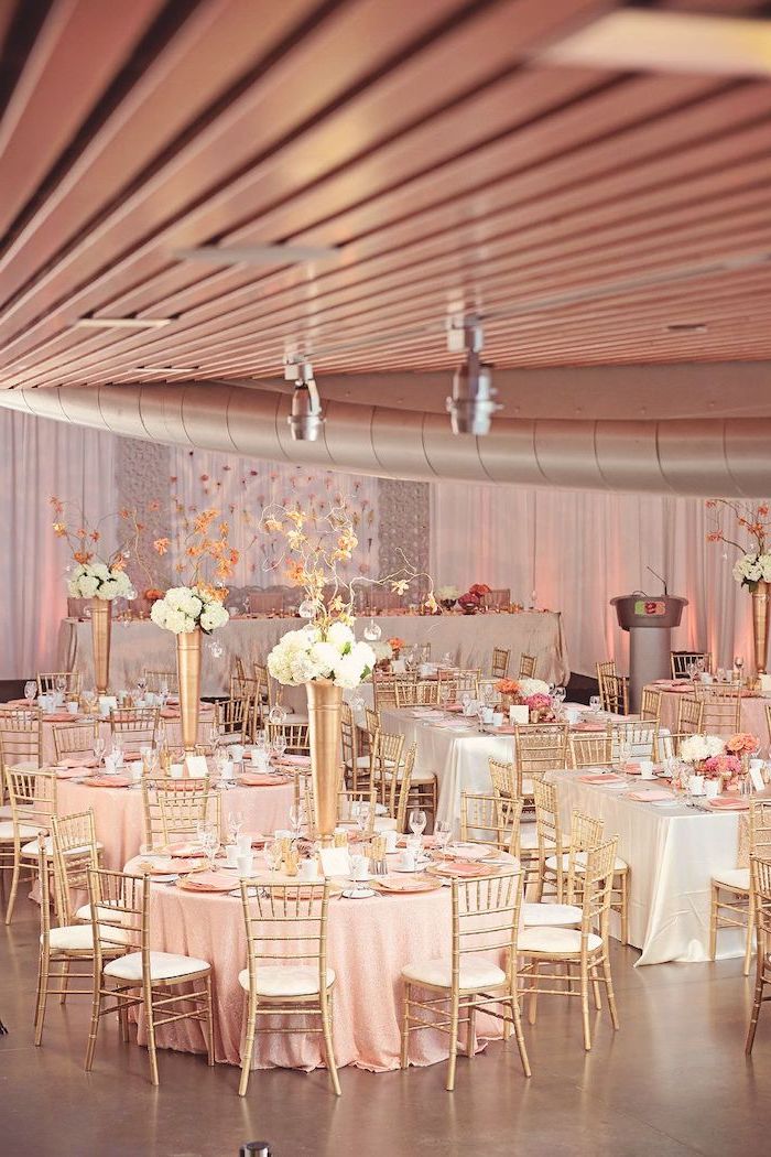 rose gold theme, white flower bouquets in high vases on the tables, ceiling hanging decor