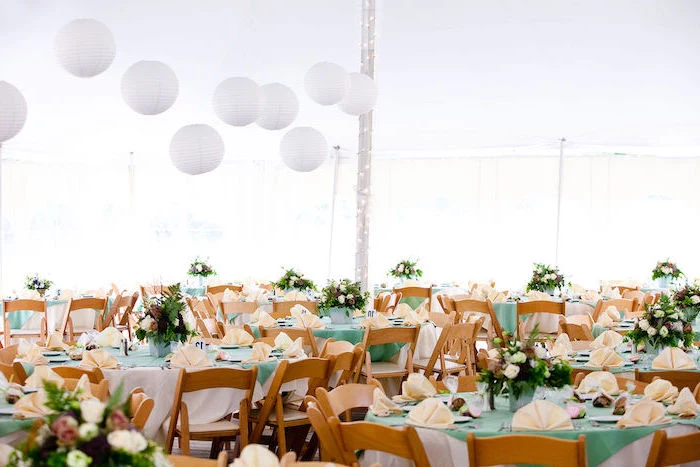 hanging lanterns, white and pink roses flower arrangements on the tables, orange napkins, wedding decor