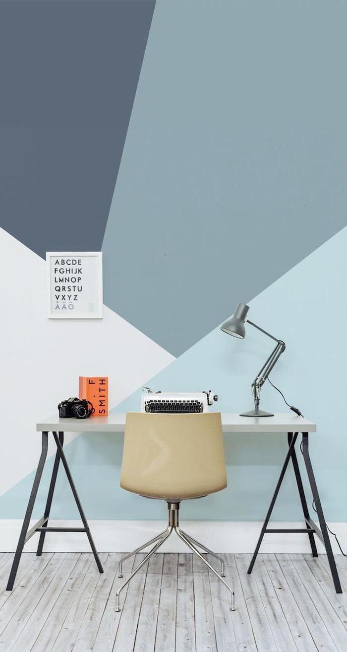 wooden desk, beige plastic chair, small home office desk, shades of blue geometrical wall, metal desk lamp