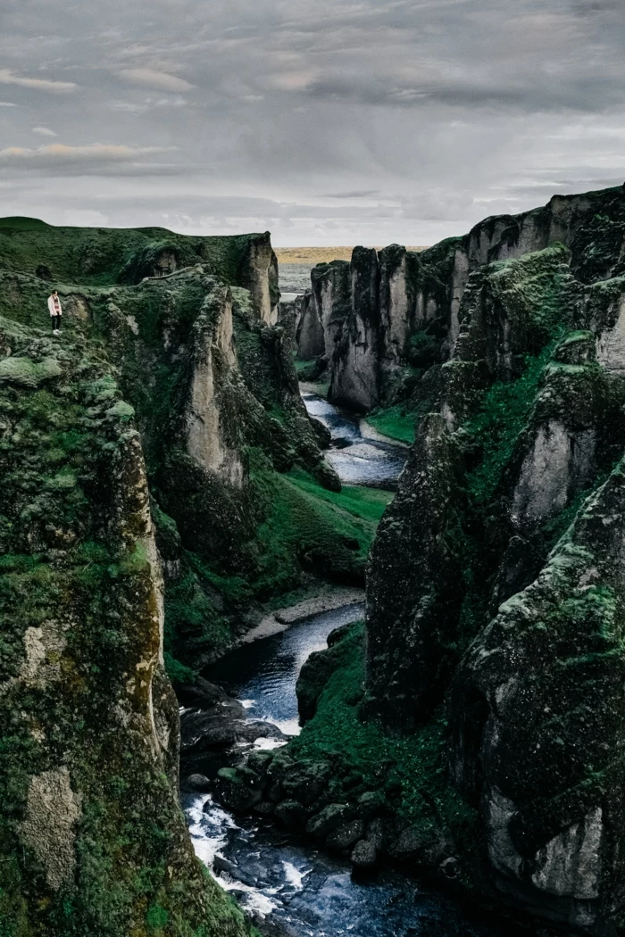 man on top of a a rock, mountains and a river, iphone wallpaper high quality, grey sky