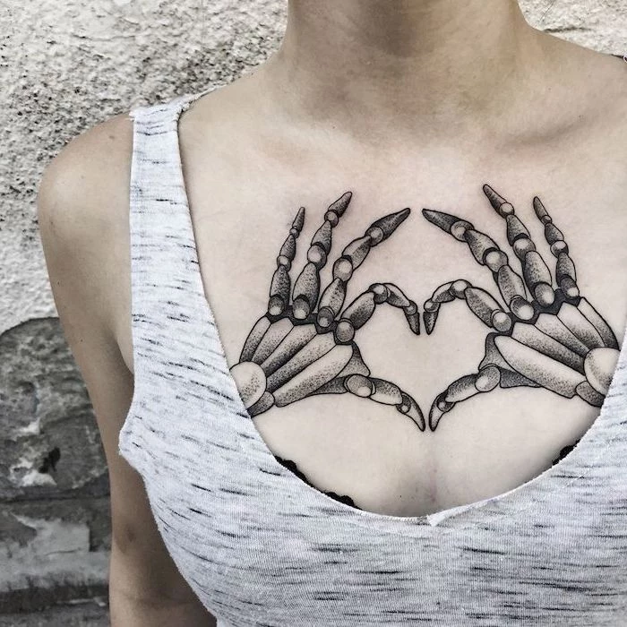 grey top and background, skeleton hands, heart shaped tattoo, tattoos for women, small chest tattoos for females