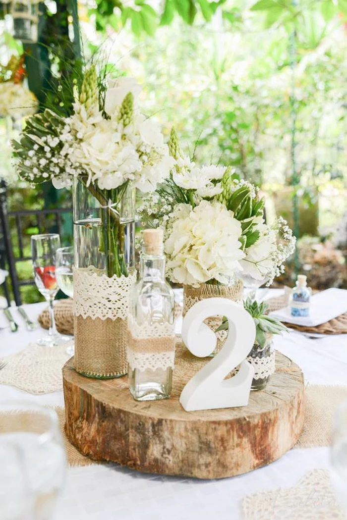 wooden centrepiece with a table number, white flower bouquets in vases, diy wedding decorations