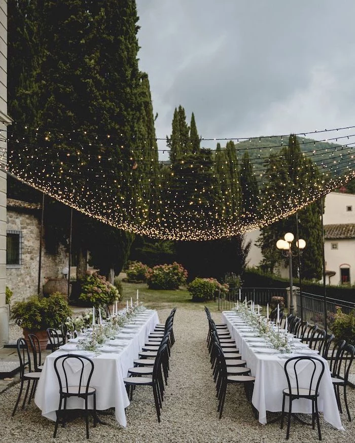 hanging fairy lights, white candles in candlesticks on the table, long tables, wedding ideas for spring