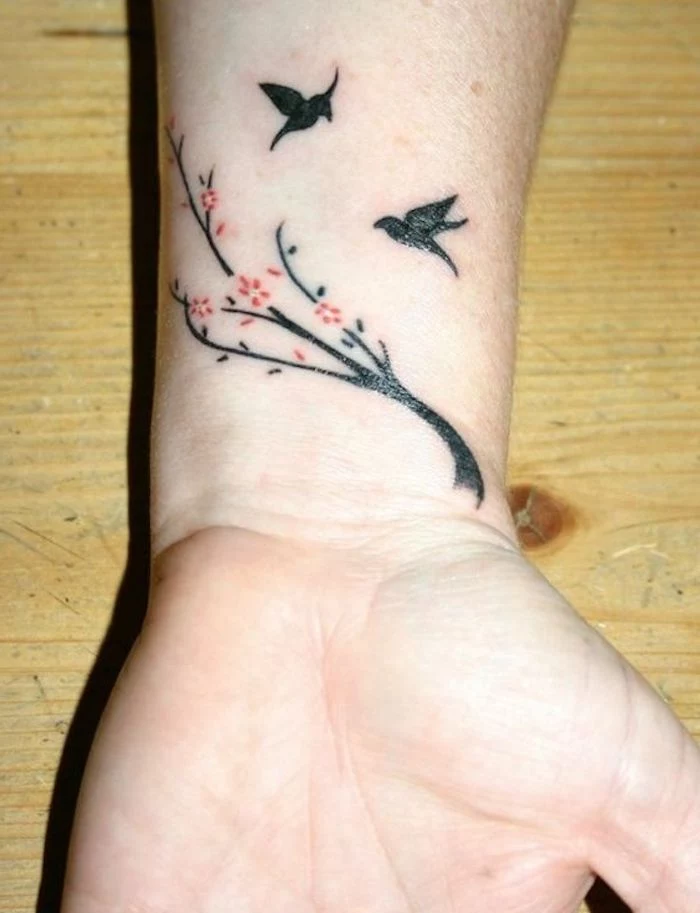 wooden table, meaningful tattoo ideas, birds and a tree brunch, wrist tattoo