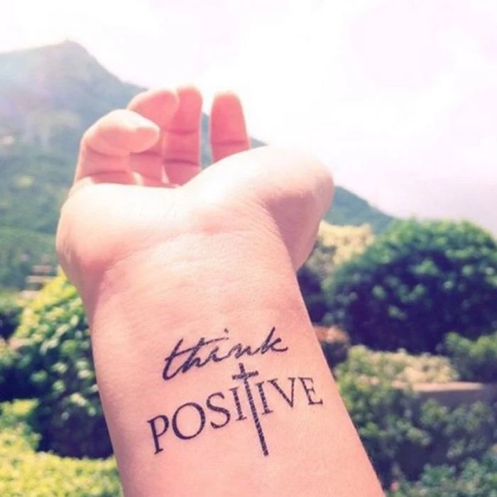 think positive inscription, chest tattoos for females, tattoo on the wrist, mountain in the background
