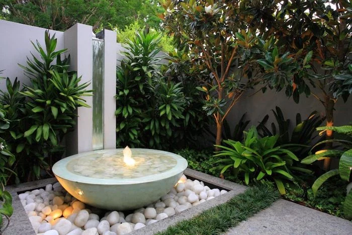 small ceramic water fountain, patch of white rocks, patches of bushes and small trees, landscape border ideas