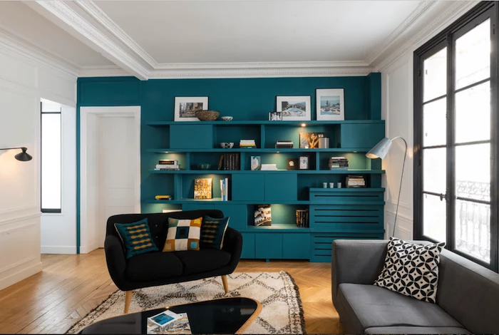 black velvet sofa, grey sofa, turquoise wall with bookshelves and cabinets, wallpaper accent wall