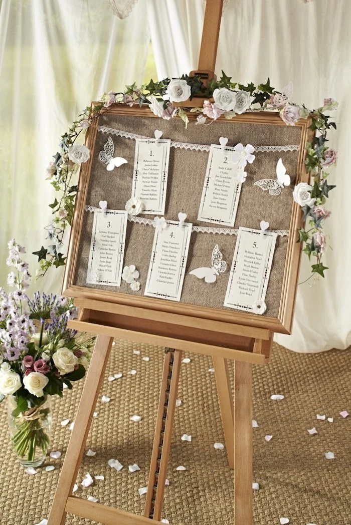 wooden stand with hanging white roses, paper pinned with pins on a white string, rose petals on the floor, wedding reception decoration ideas