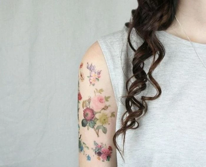 flower bouquets on shoulder, brown curly hair, small tattoo ideas for men, grey top, white background