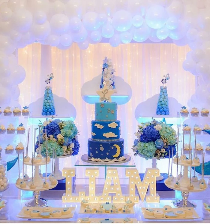 white balloon arch, cake and sweets on the table, baby boy baby shower themes, liam lights on the table