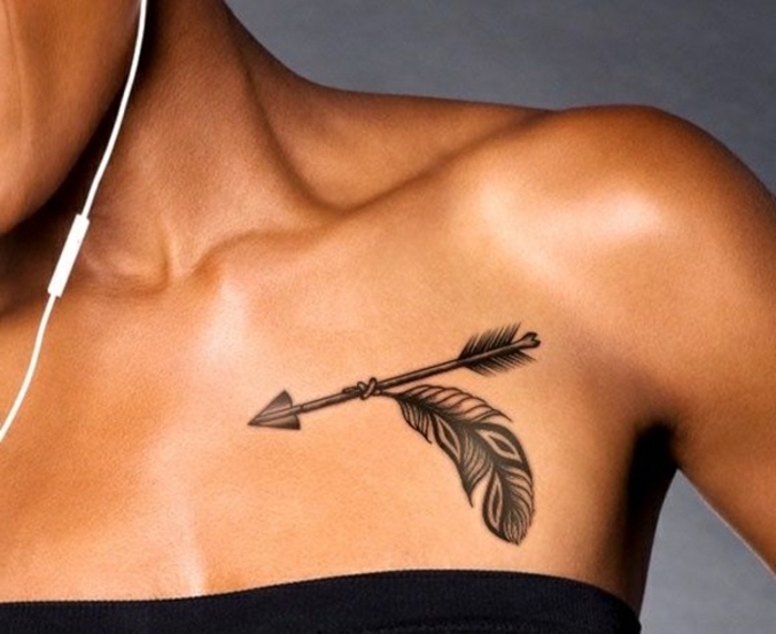 black top, arrow and feather tattoo on shoulder, chest tattoos for females, grey background