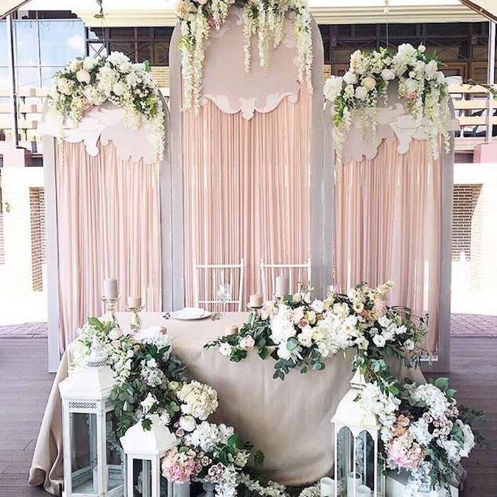 backdrop with blush tulle and hanging white flowers , white lanterns with flower arrangements, wedding ideas for summer