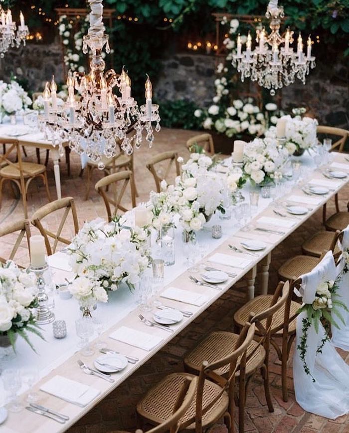 hanging candelabrum chandeliers, white roses flower bouquets on the table, candles on candlesticks, hanging decorations