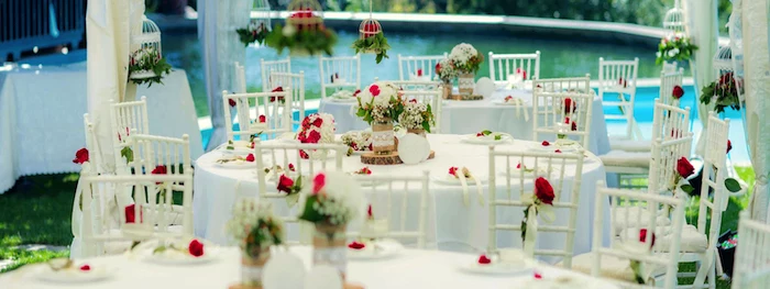 hanging bird cages with flowers, red roses in vases on the tables, white and red roses flower bouquets, hanging decorations