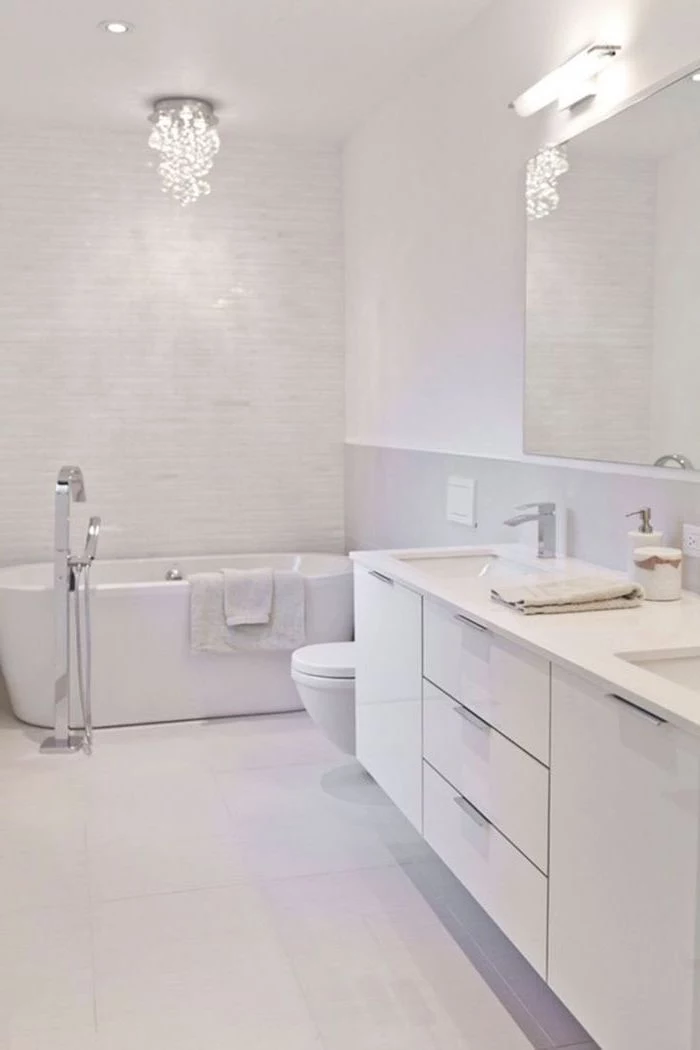 white tiled floor and walls, white floating cabinets, bathroom wall ideas, hanging chandelier