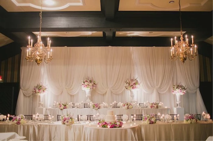 white tulle backdrop, candelabrum chandeliers with candles, pink and white flower bouquets in large vases, rustic wedding centrepieces