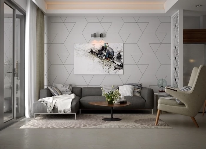 white geometrical wallpaper, dark grey corner sofa, painting accent walls, large white armchair