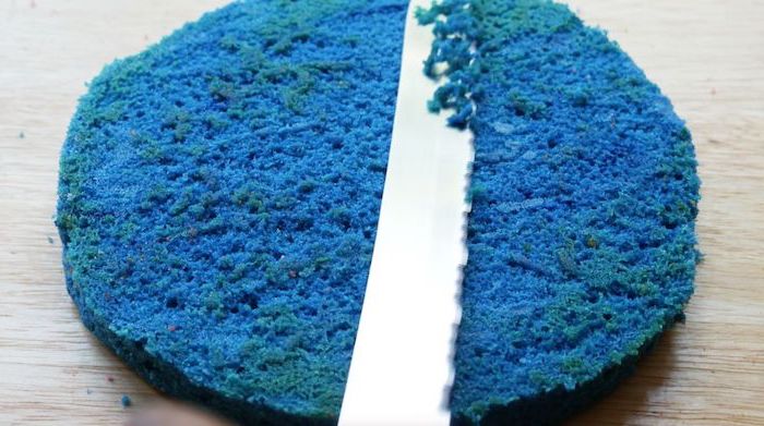 knife cutting through blue batter, unicorn cupcakes, crumbs on the wooden countertop