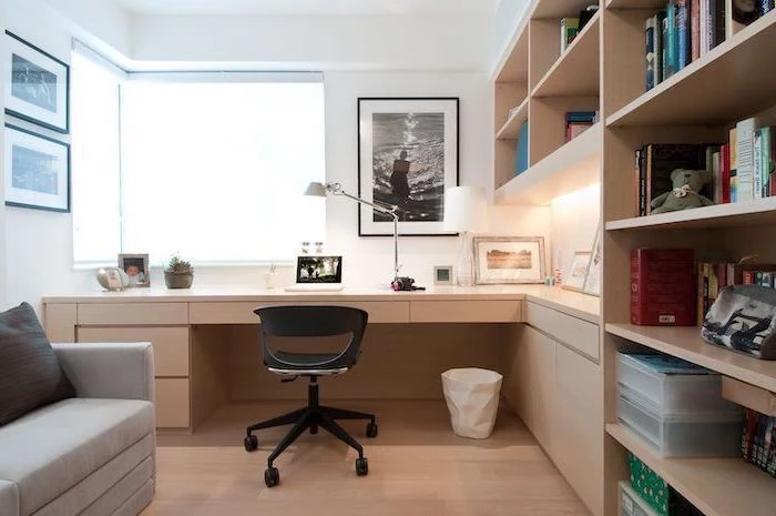 wooden bookcase with shelves and cabinets, work office decor, grey sofa, black chair, white walls with framed photos