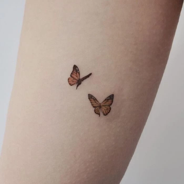 two yellow butterflies, back tattoos for girls, tattoo on the forearm, white background