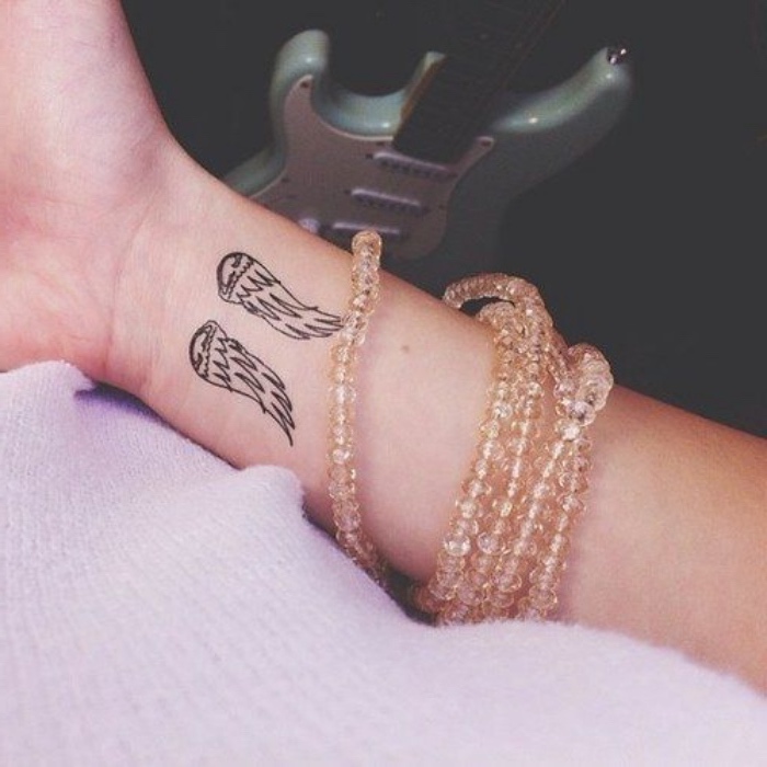 angel wings wrist tattoo, guitar in the background, lots of bracelets, small tattoo ideas