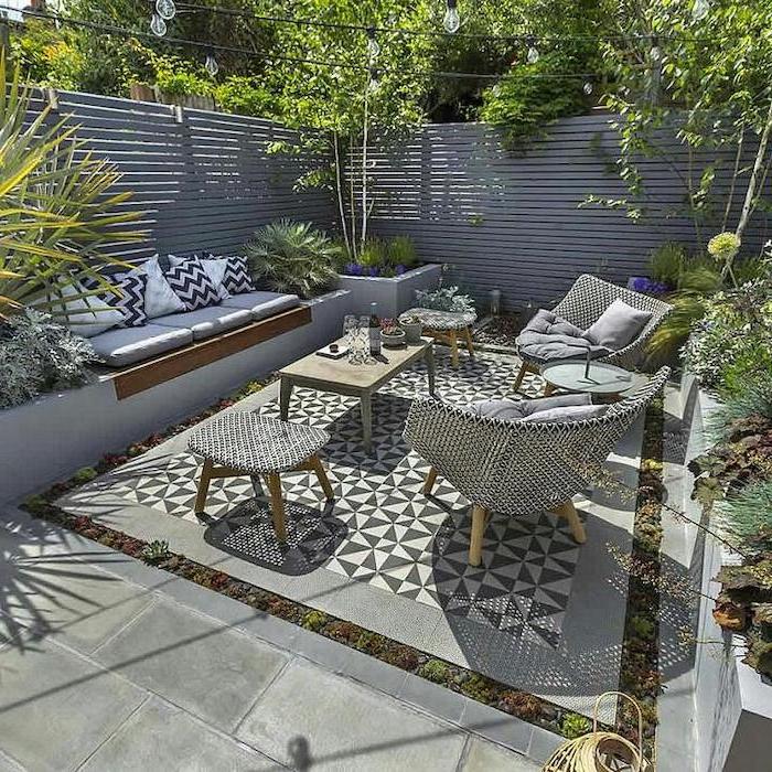 wooden garden furniture, small patio ideas, planted trees and bushes, cement tiles, wooden walls