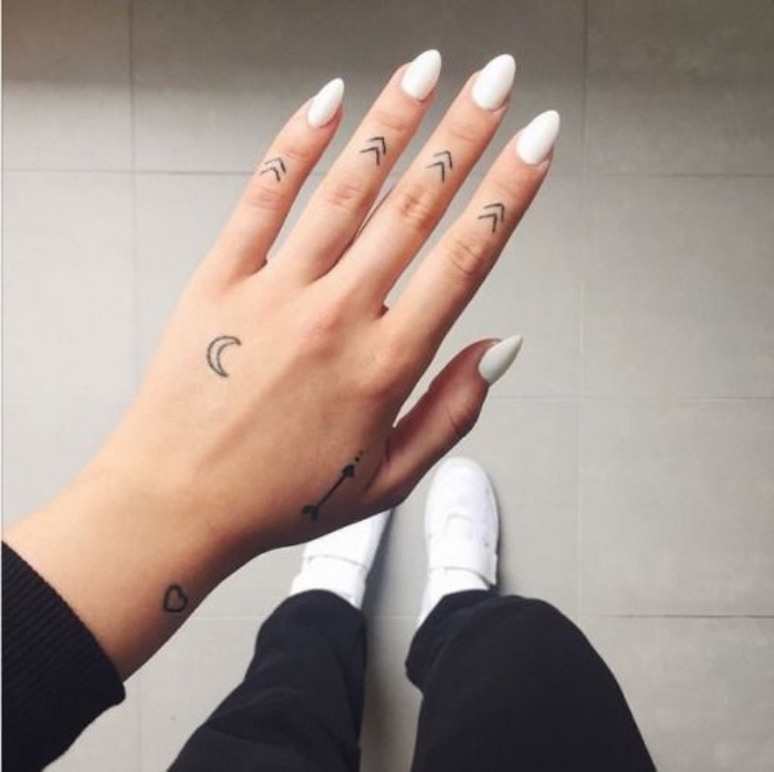 arrows moon and heart hand tattoos, small tattoos for men, woman wearing white nail polish, white sneakers