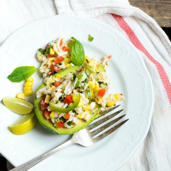 avocado salad, with corn and meat, basil and lemon slices on the side, healthy eating plans, in a white plate