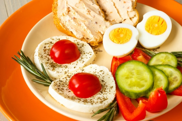 mozzarella with tomatoes, boiled egg, vegetables and bread, in a white plate, healthy weekly meal plan