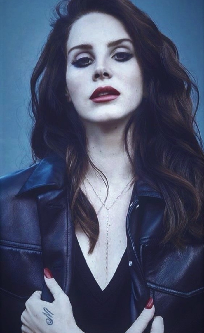 small tattoos, lana del rey looking at the camera, wearing black leather jacket, small m letter hand tattoo