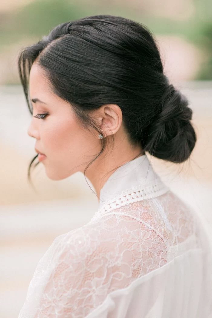 black hair, in a low updo, wedding hairstyles for long hair, white dress with lace