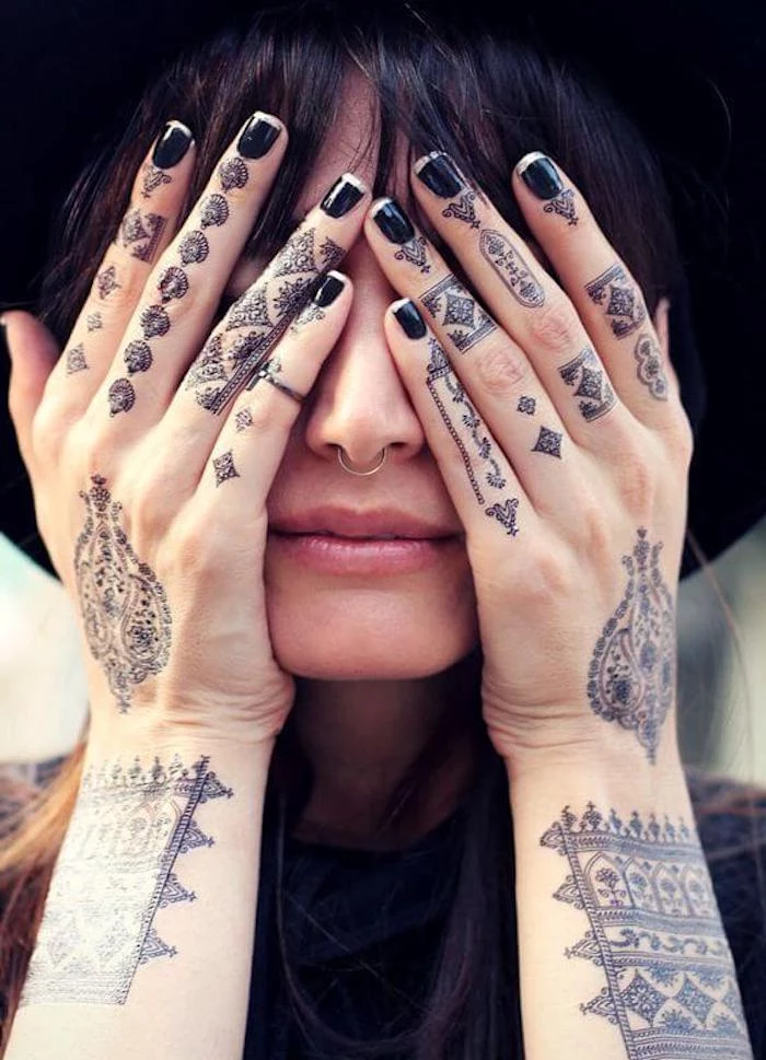 black nail polish, finger tattoo ideas, henna tattoos, many finger tattoos, woman covering her face