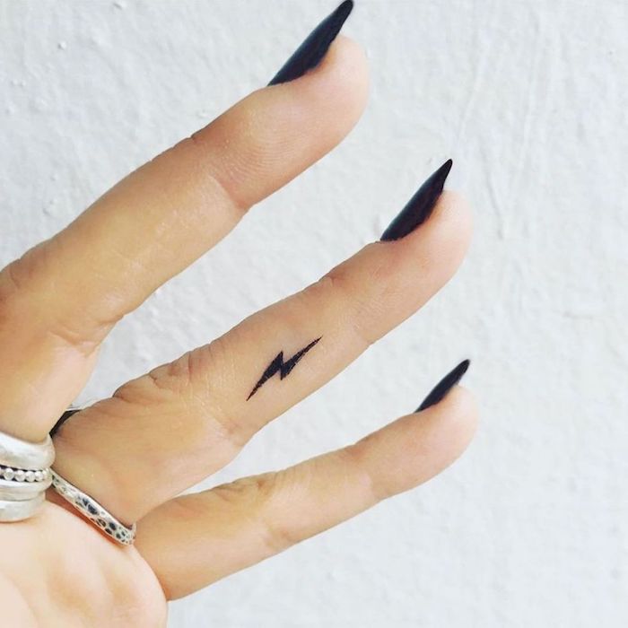 long black stiletto nails, small lighting bolt, ring finger tattoo, finger tattoo ideas, silver rings, white background