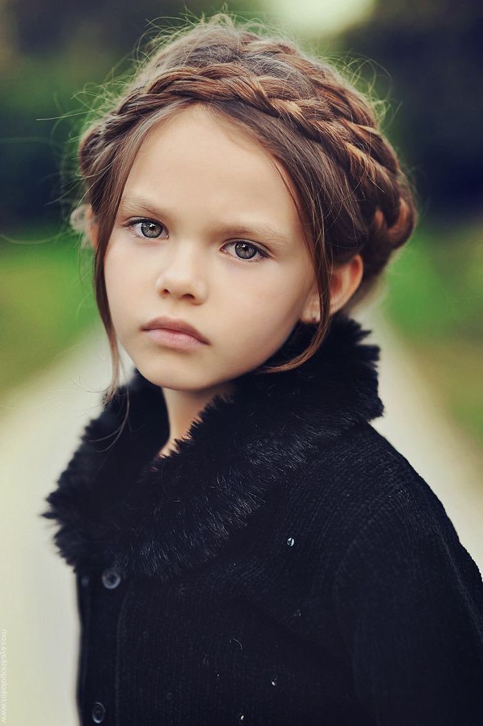black fluffy cardigan, long brown braided hair, little girl hairstyles, green eyes, blurred background